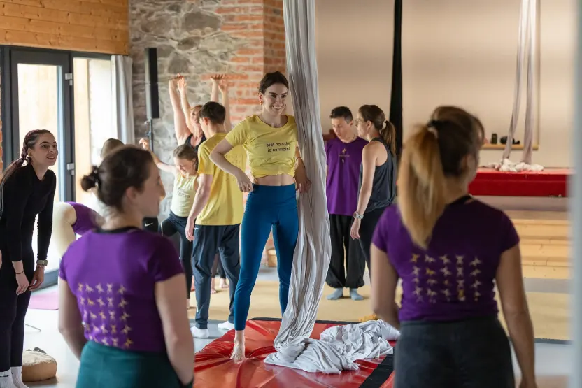Lektorka předvádí prvek závěsné akrobacie, účastníci retreatu se dívají
